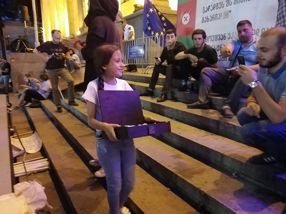 ანტისაოკუპაციო აქციის მონაწილეებს ბავშვი ტკბილეულს ურიგებს
